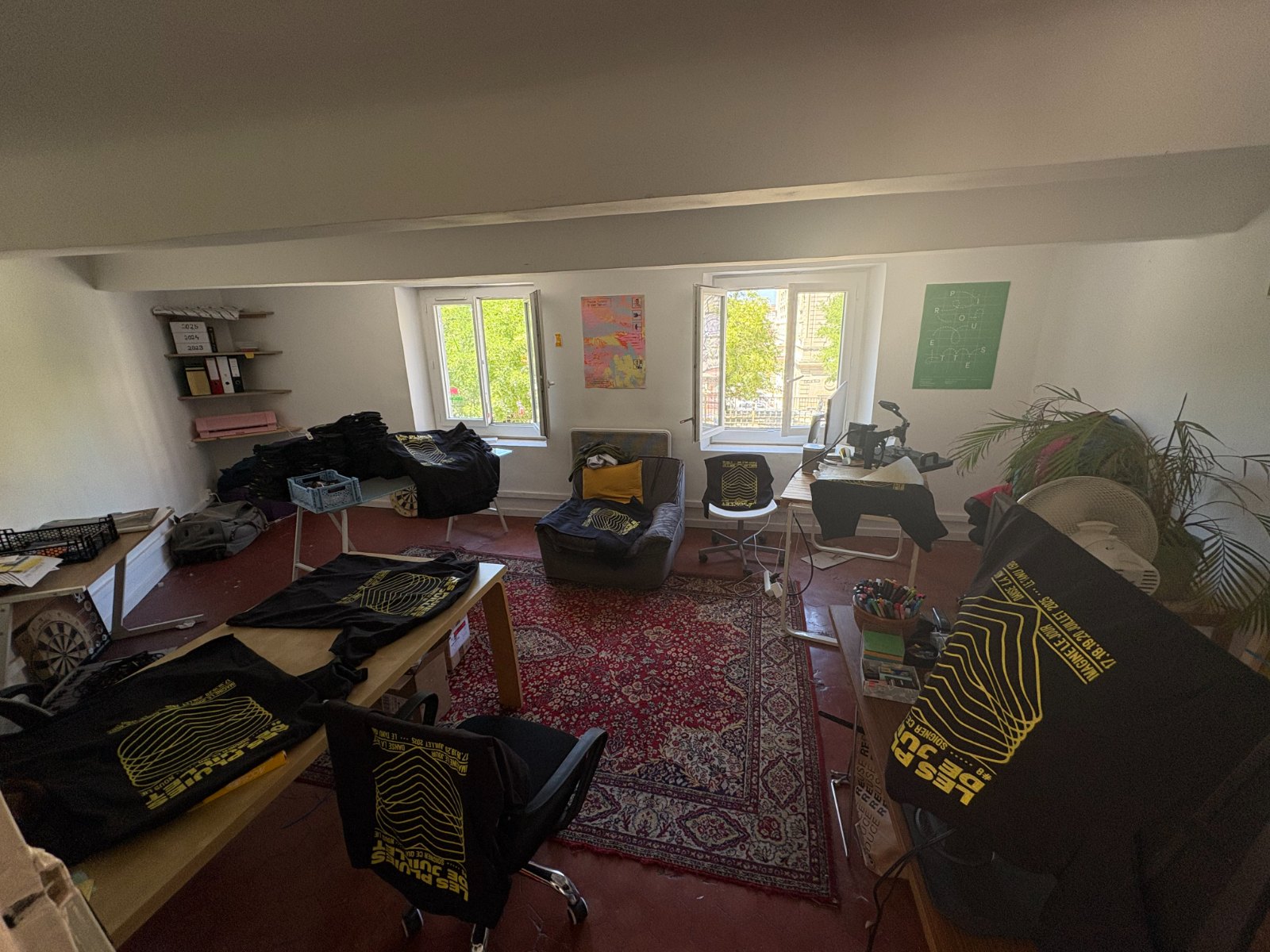 Vue large de l'atelier marseillais, t-shirts étalés sur les tables