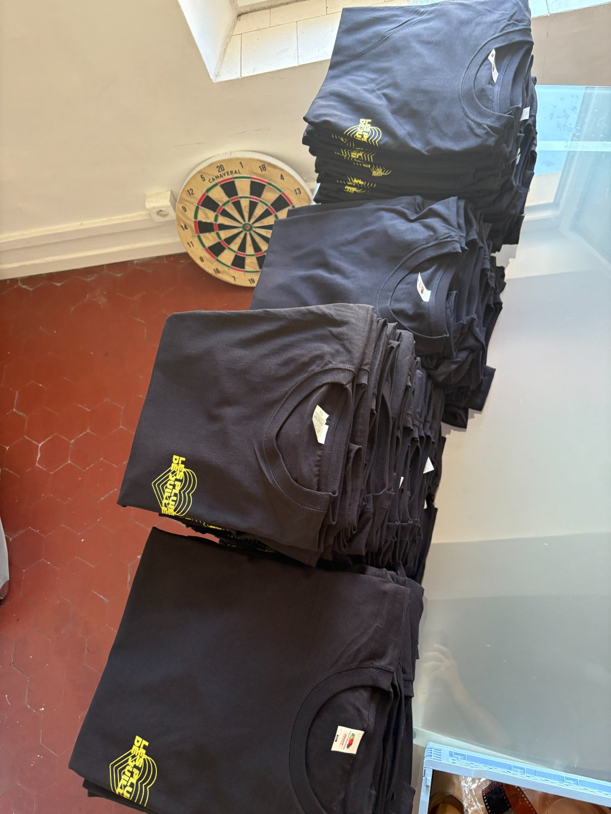 Piles de t-shirts noirs sérigraphiés Les Pluies de Juillet
