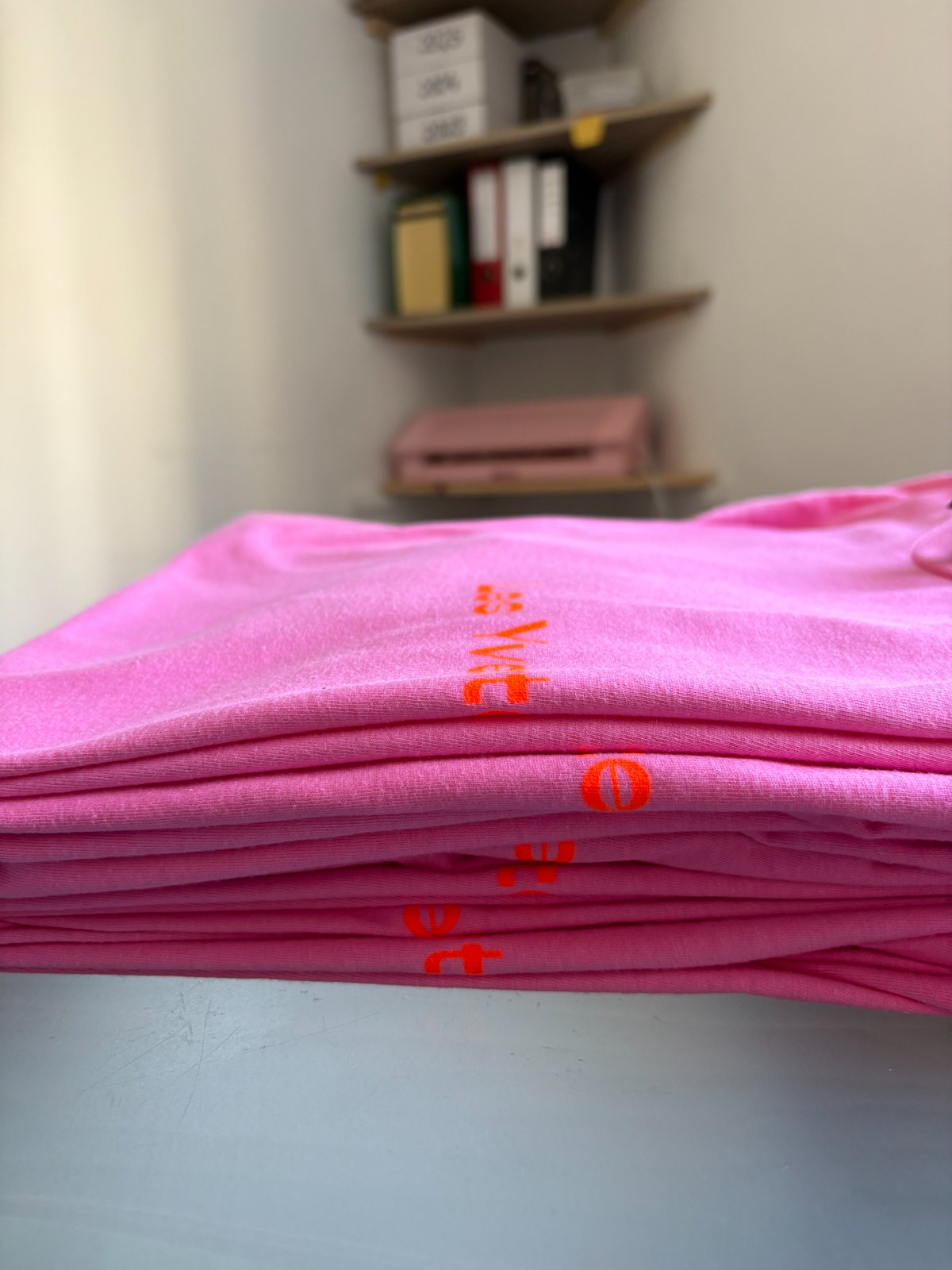 Détail de t-shirts roses sérigraphiés en orange